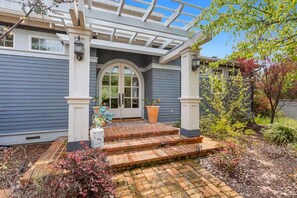 A house with a covered porch, a front door with glass panels, and a brick pathway leading to the entrance. - Riverfront Paradise at RedRock Villa (Three Rivers)