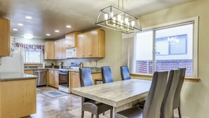 A kitchen with wooden cabinets, a dining table with chairs, a built-in oven, and a window with blinds. - Tahoe Town & Lake Retreat - Near Tahoe Keys (South Lake Tahoe)