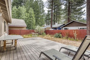 A wooden deck with a table and chairs, surrounded by a red fence and trees. - Tahoe Town & Lake Retreat - Near Tahoe Keys (South Lake Tahoe)