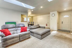 A living room with a sectional sofa, a small ottoman, a dining table, and a ceiling skylight. - Tahoe Town & Lake Retreat - Near Tahoe Keys (South Lake Tahoe)