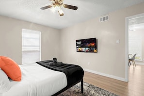 A bedroom with a bed, a ceiling fan, a TV mounted on the wall, and a window with blinds. - Austin Medical Hub | Cozy 1BR | Free Parking (Austin)