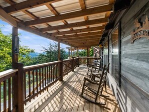 Eine Holzterrasse mit Holzgeländer, einem Schaukelstuhl und Blick auf die Berge.