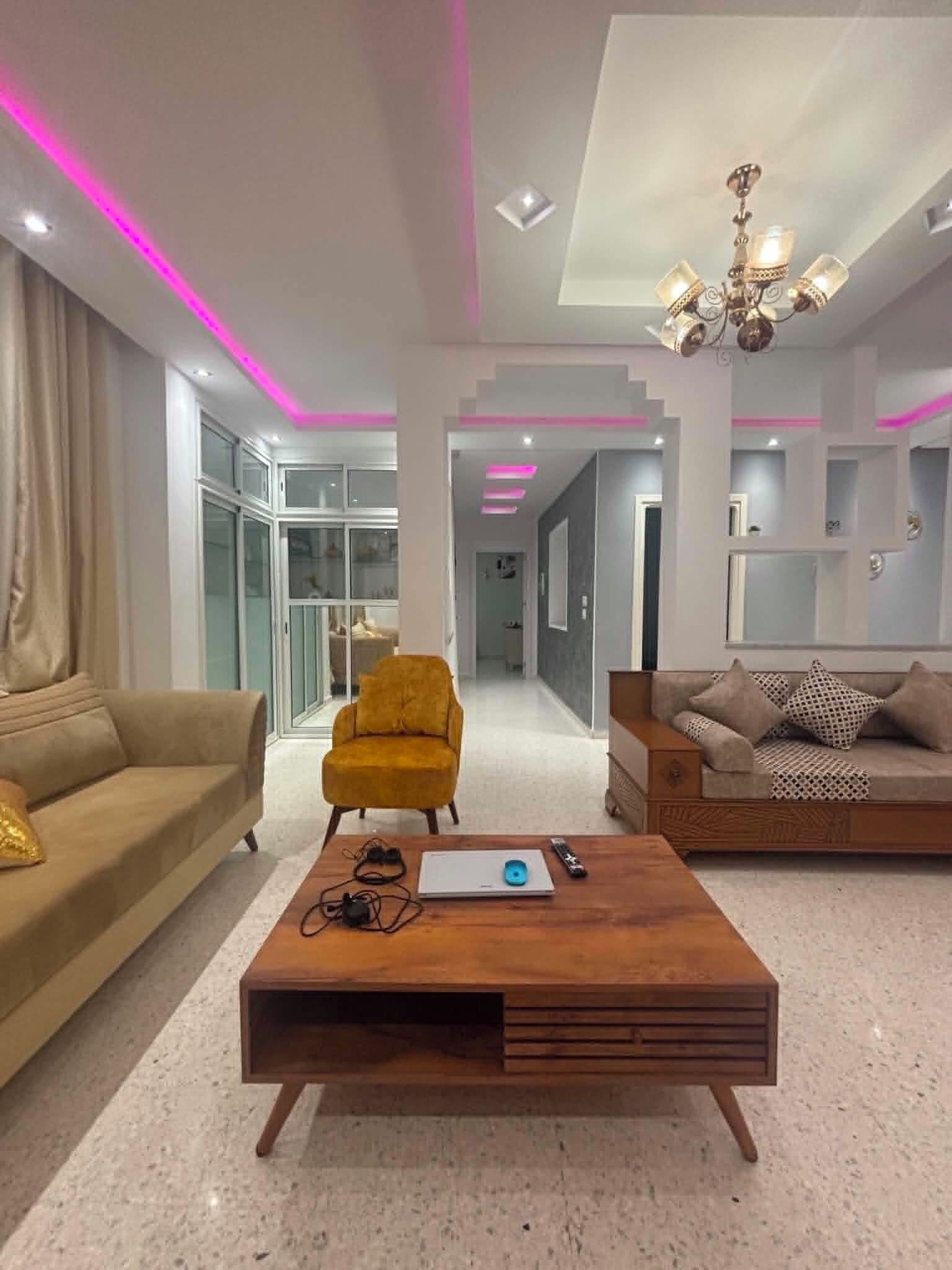 A modern living room with a sofa, armchair, coffee table, and a chandelier.