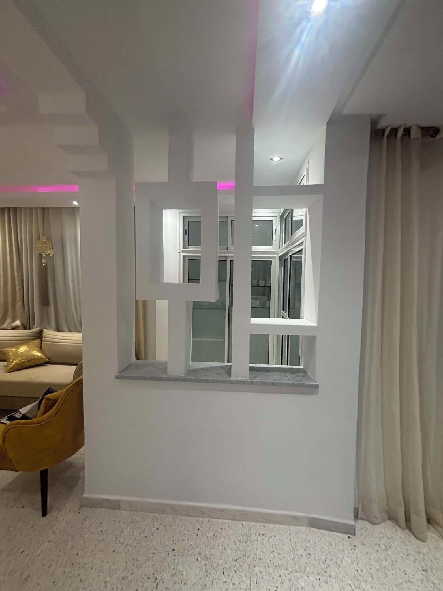 A room with a built-in window, a sofa, and a chair.