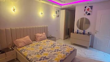 A bedroom with a bed, bedside tables, a vanity, and a mirror.