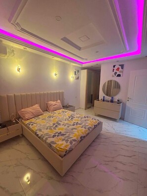 Une chambre à coucher comprenant un lit, des tables de chevet, une coiffeuse et un miroir.