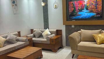 Ein modernes Wohnzimmer mit Wand-Fernseher, einer Sofagarnitur, einem Couchtisch und einer dekorativen Stehlampe.