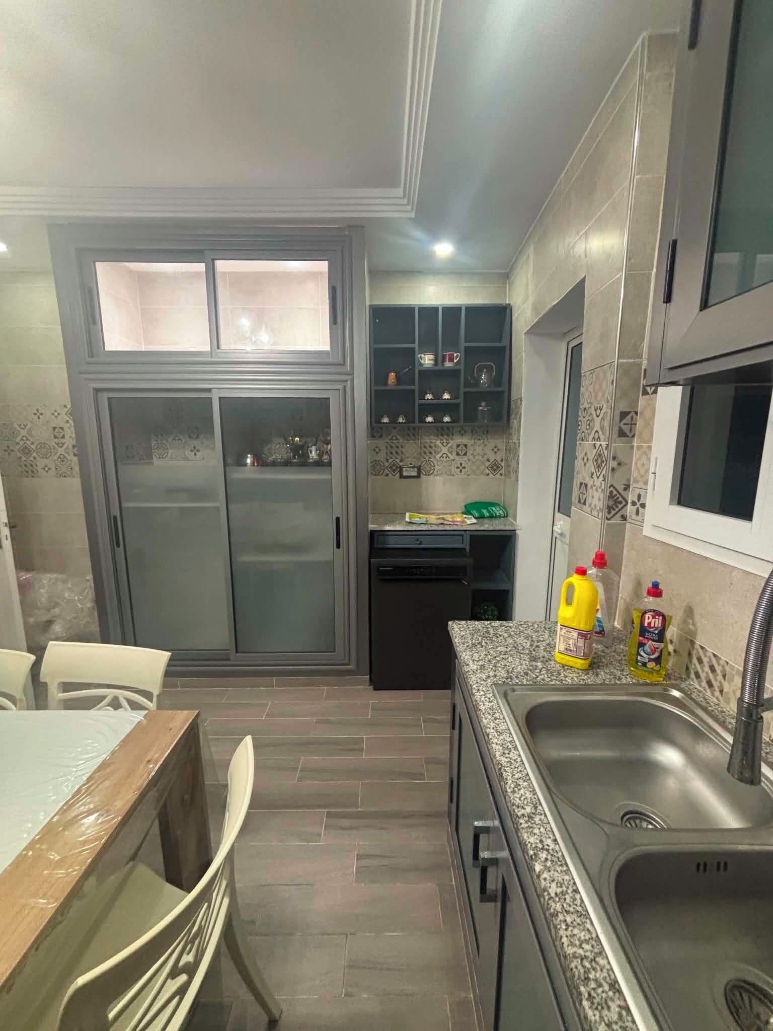 Una cocina moderna con refrigerador, pileta y comedor.