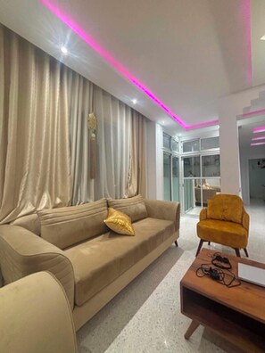 Una sala moderna con un sofá beige, un sillón amarillo y una mesa de centro.