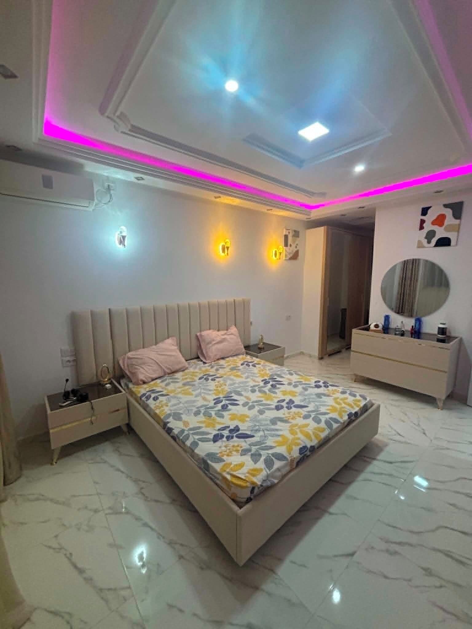 A modern bedroom with a bed, bedside tables, a dresser, and a mirror.