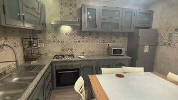 A compact kitchen with a dining area, featuring a microwave, stove, and cabinets.