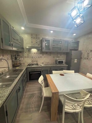 A compact kitchen with a dining area, featuring a microwave, stove, and cabinets.