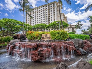 Un hôtel doté d’une cascade, d’une végétation luxuriante et offrant une vue sur un ciel dégagé.