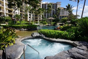 Un espace piscine d’hôtel doté d’un jacuzzi, entouré d’une végétation luxuriante et de palmiers.