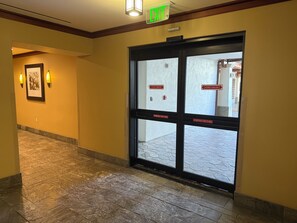 Ein Hotel Eingang mit Glastür, Ausgangsschild und Notfallanweisungen.