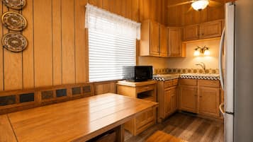 Eine Küche mit Holzwandverkleidung, einem Holztisch, einer Mikrowelle und einem Kühlschrank.