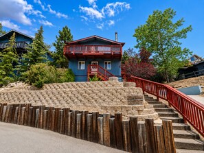A multi-story building with a red balcony, stone steps, and a wooden fence. - The Moonridge Escape (Big Bear Lake)