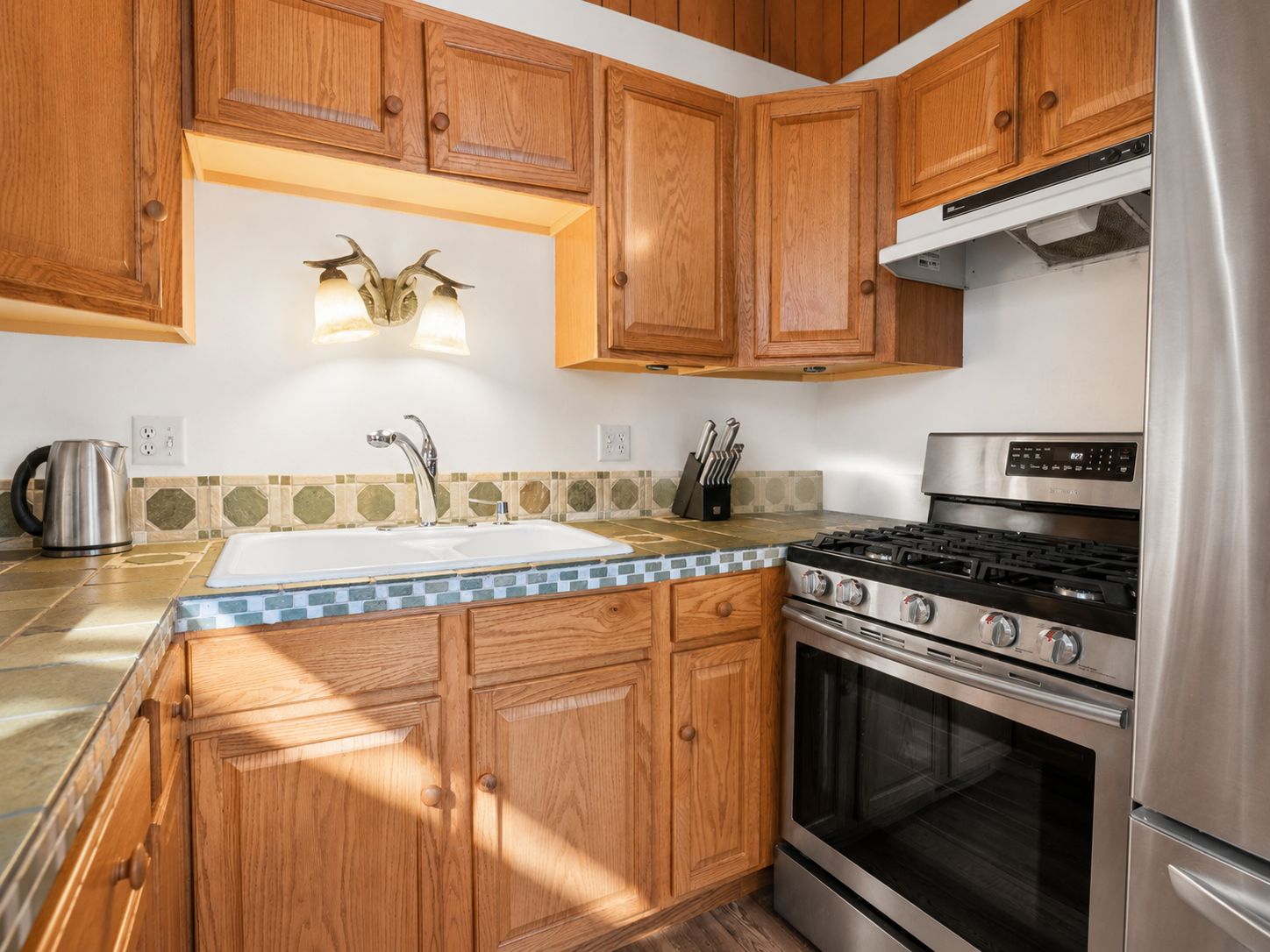 Una cocina con gabinetes de madera, una estufa de acero inoxidable y un fregadero.