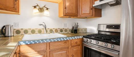 A kitchen with wooden cabinets, a stainless steel stove, and a sink.