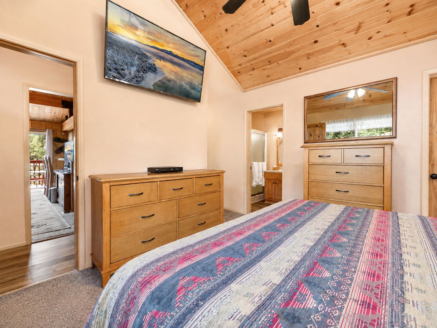 A bedroom with a large bed, wooden dresser, and a painting on the wall.