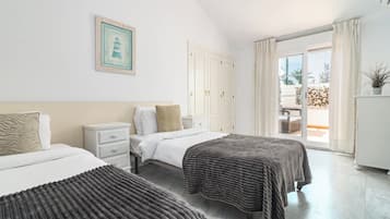 Une chambre d’hôtel avec deux lits, une table de chevet, une armoire et un balcon avec vue.