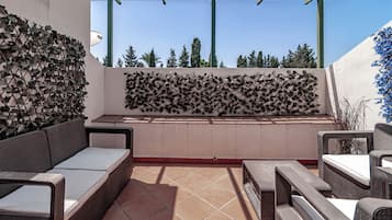 Un espace extérieur aménagé, abrité et doté d’une pergola, d’un mur fait d’une pile de bûches et offrant une vue sur les arbres et le ciel.