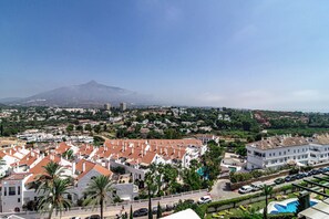 A residential area with white buildings, a mountain in the background, and a clear sky. - Sam65i Central 2 Bed Penthouse in Nueva Andalucia (Marbella)