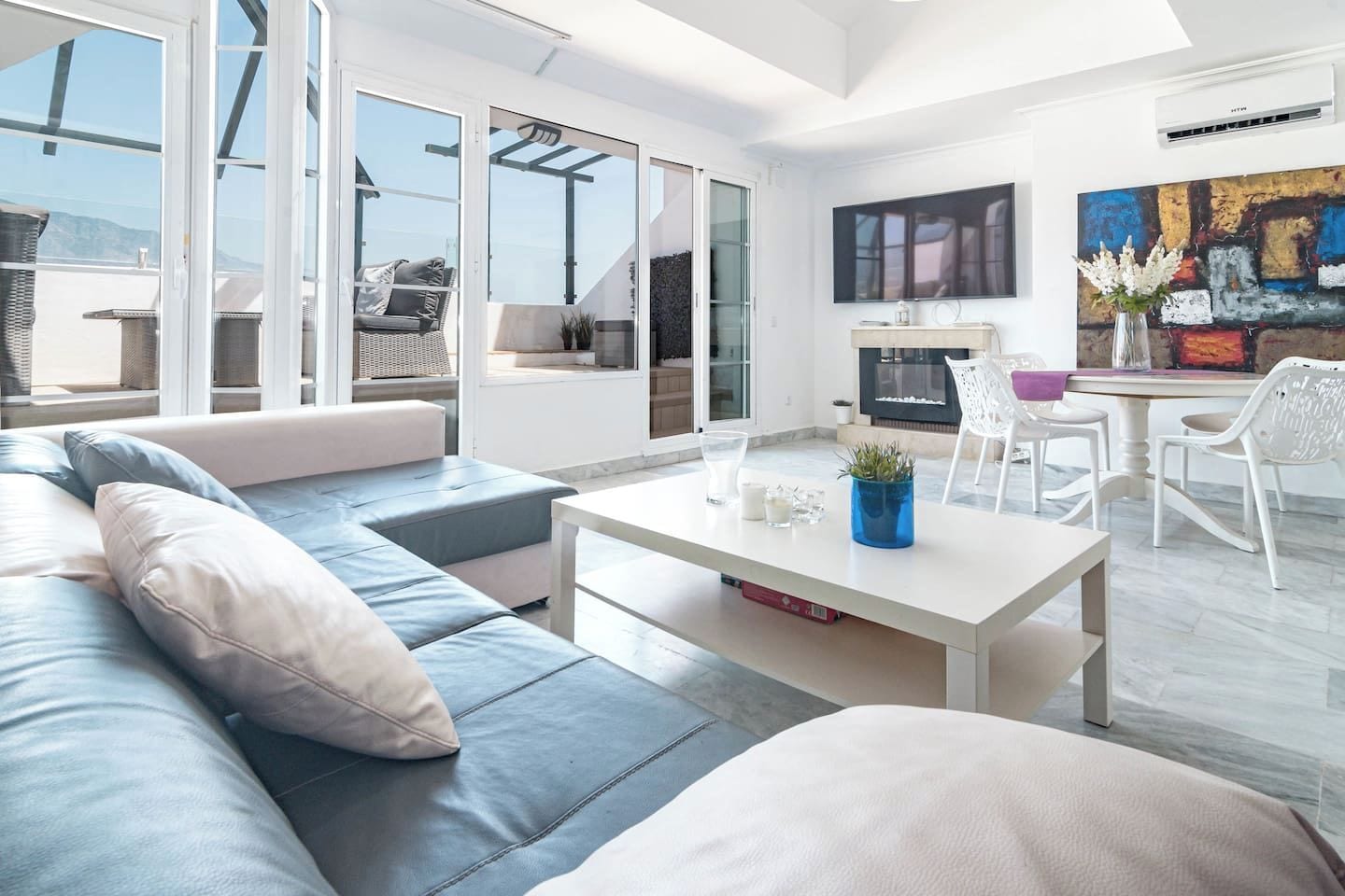 Un salon moderne comprenant un canapé, une table basse et un coin repas avec des chaises.