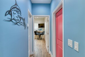 A hallway with a blue wall, a red door, and a dining area with a table and chairs. - Private Beach Access, Ocean Views, Hot Tub, Balcony, Brand New Furnishings, $300 in Free Tickets! (St. Augustine)