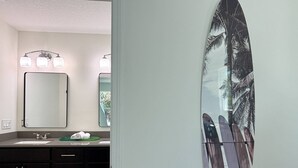 A bathroom with a large mirror, two wall-mounted lights, a sink, and a towel rack. - Private Beach Access, Beautiful Ocean Views, Balcony, Brand New Furnishings, $300 in Free Tickets! (St. Augustine)