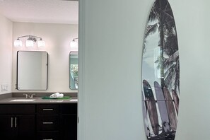 A bathroom with a large mirror, two wall-mounted lights, a sink, and a towel rack. - Private Beach Access, Beautiful Ocean Views, Balcony, Brand New Furnishings, $300 in Free Tickets! (St. Augustine)