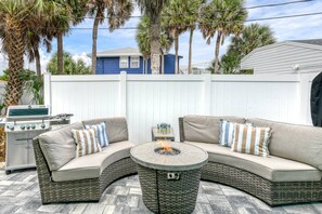 A curved outdoor seating area with a round table and a grill.