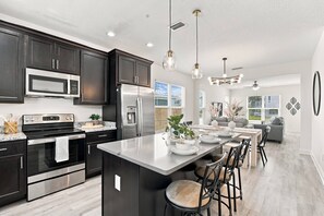 A modern kitchen with dark cabinetry, stainless appliances, and a central island with bar stools.