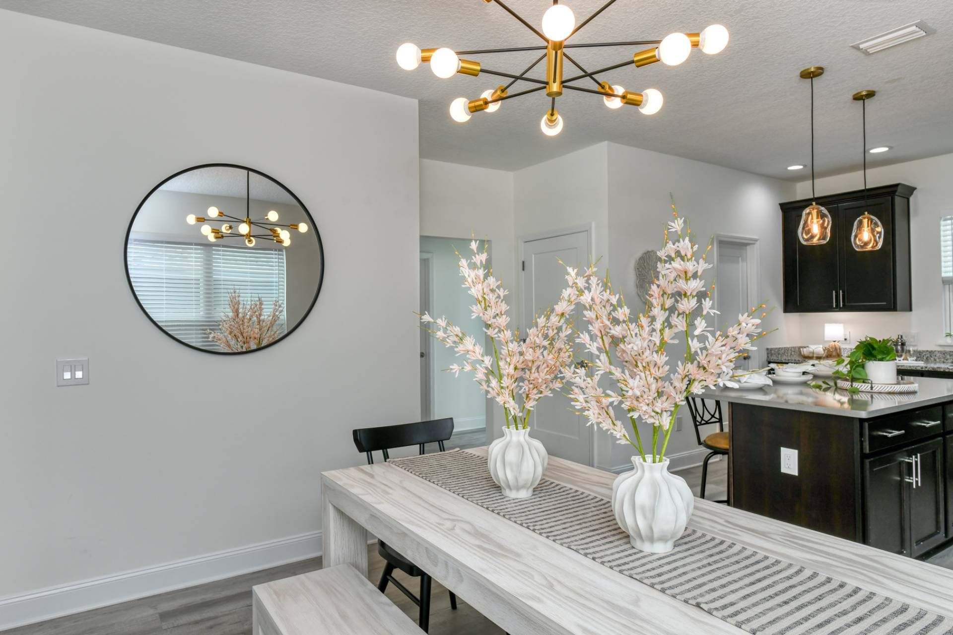 A modern kitchen with dark cabinets, a marble countertop, and a pendant light.