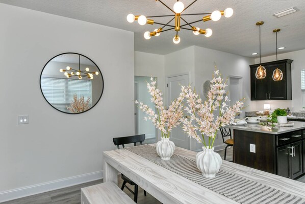 A modern kitchen with dark cabinets, a marble countertop, and a pendant light.