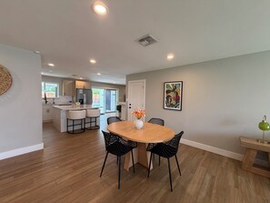 A modern kitchen with a central island, a dining area with a round table and chairs, and a view to the outside. - The Cove: Poolside Getaway near PV & Camelback (Phoenix)