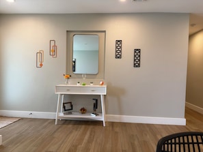 A room with a white vanity, a mirror, a clock, and decorative wall art. - The Cove: Poolside Getaway near PV & Camelback (Phoenix)