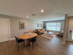 A spacious living area with a wooden dining table, black chairs, a sofa, and a coffee table. - The Cove: Poolside Getaway near PV & Camelback (Phoenix)
