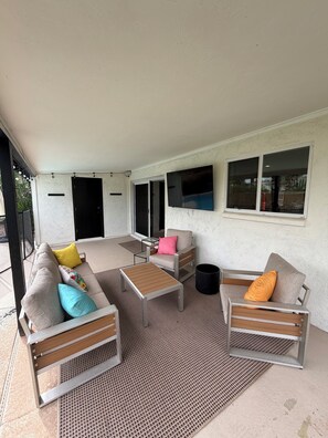 Un espace extérieur aménagé avec un canapé, des fauteuils et une table basse.