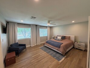 A bedroom with a bed, a chair, a nightstand, a ceiling fan, and a window with blinds. - The Cove: Poolside Getaway near PV & Camelback (Phoenix)