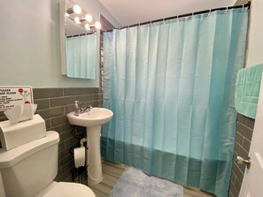 Une salle de bain avec des toilettes, un lavabo et un rideau de douche.