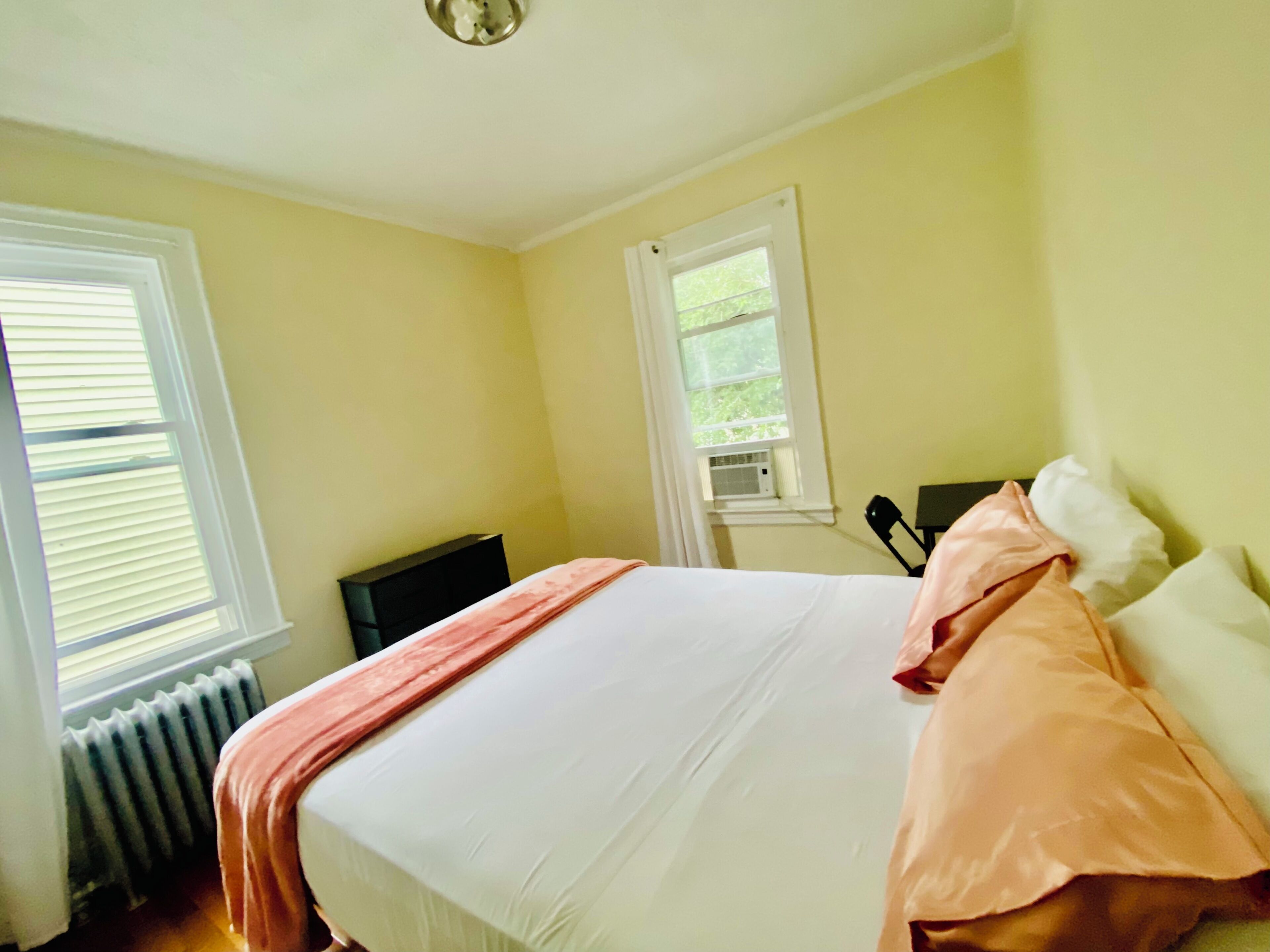 Un dormitorio con cama, radiador y ventana.