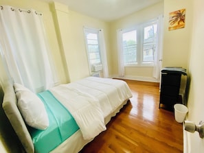 Ein Zimmer mit einem Bett, einem Heizkörper, einem Fenster und einer Tür.