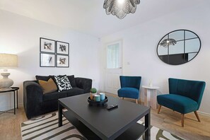 Ein modernes Wohnzimmer mit einem schwarzen Sofa, einem runden Spiegel und einem Couchtisch.
