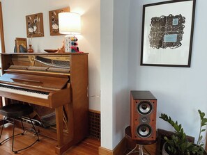 Een piano, speakers en wanddecoratie in een kamer.