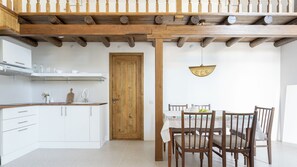 A kitchen with white cabinets, a wooden door, and a dining area with a table and chairs. - Khujra Studios (Bukhara)