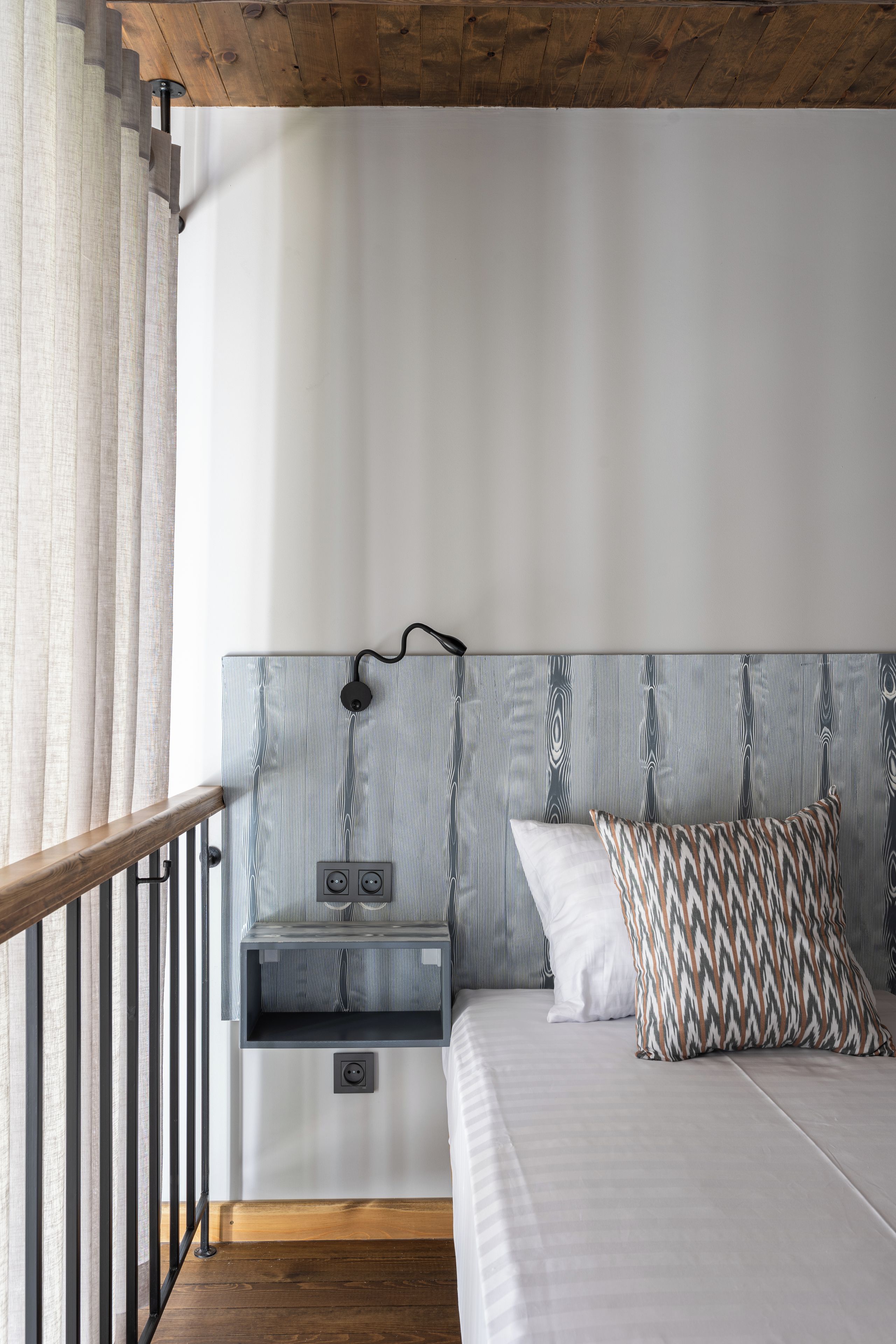 A bedroom with a bed, a nightstand, a lamp, and a window with curtains.