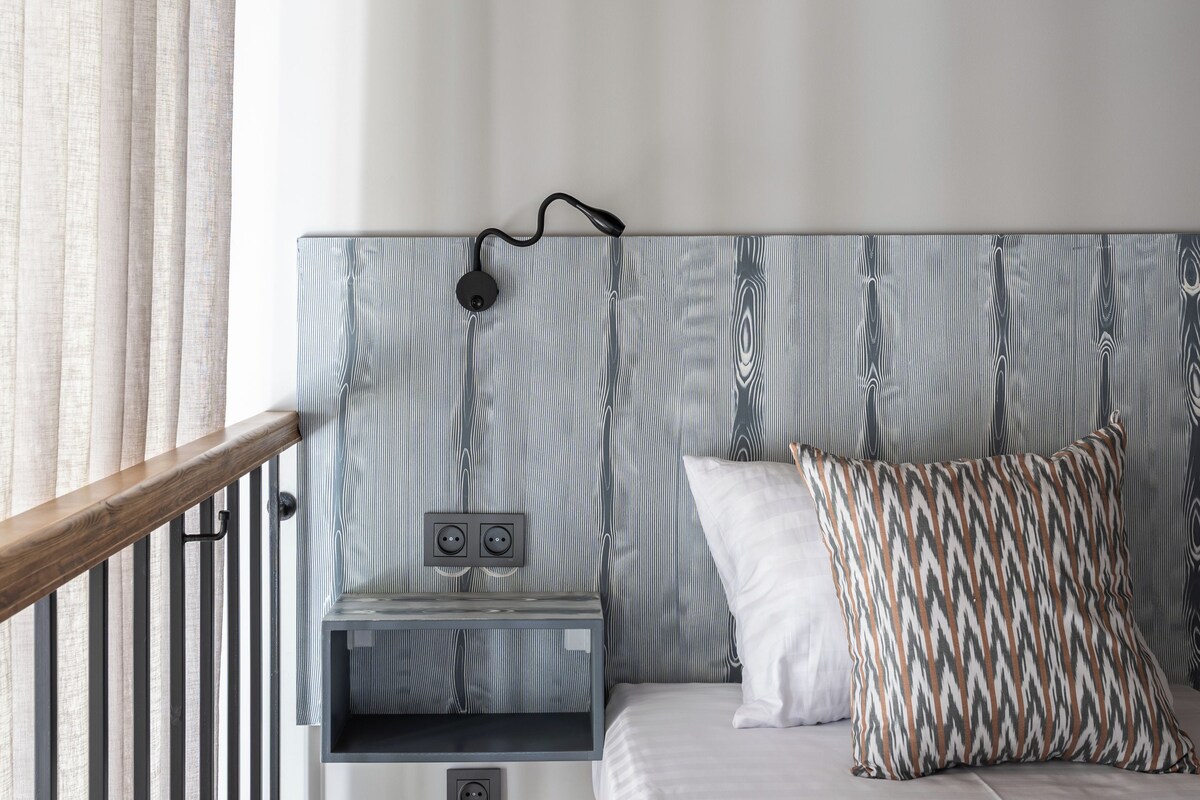 A bedroom with a bed, a nightstand, a lamp, and a window with curtains.