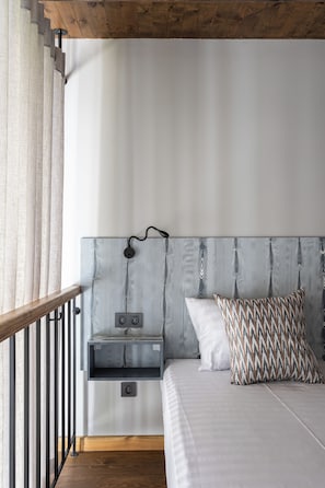 Un dormitorio con cama, mesita de noche, lámpara y ventana con cortinas.
