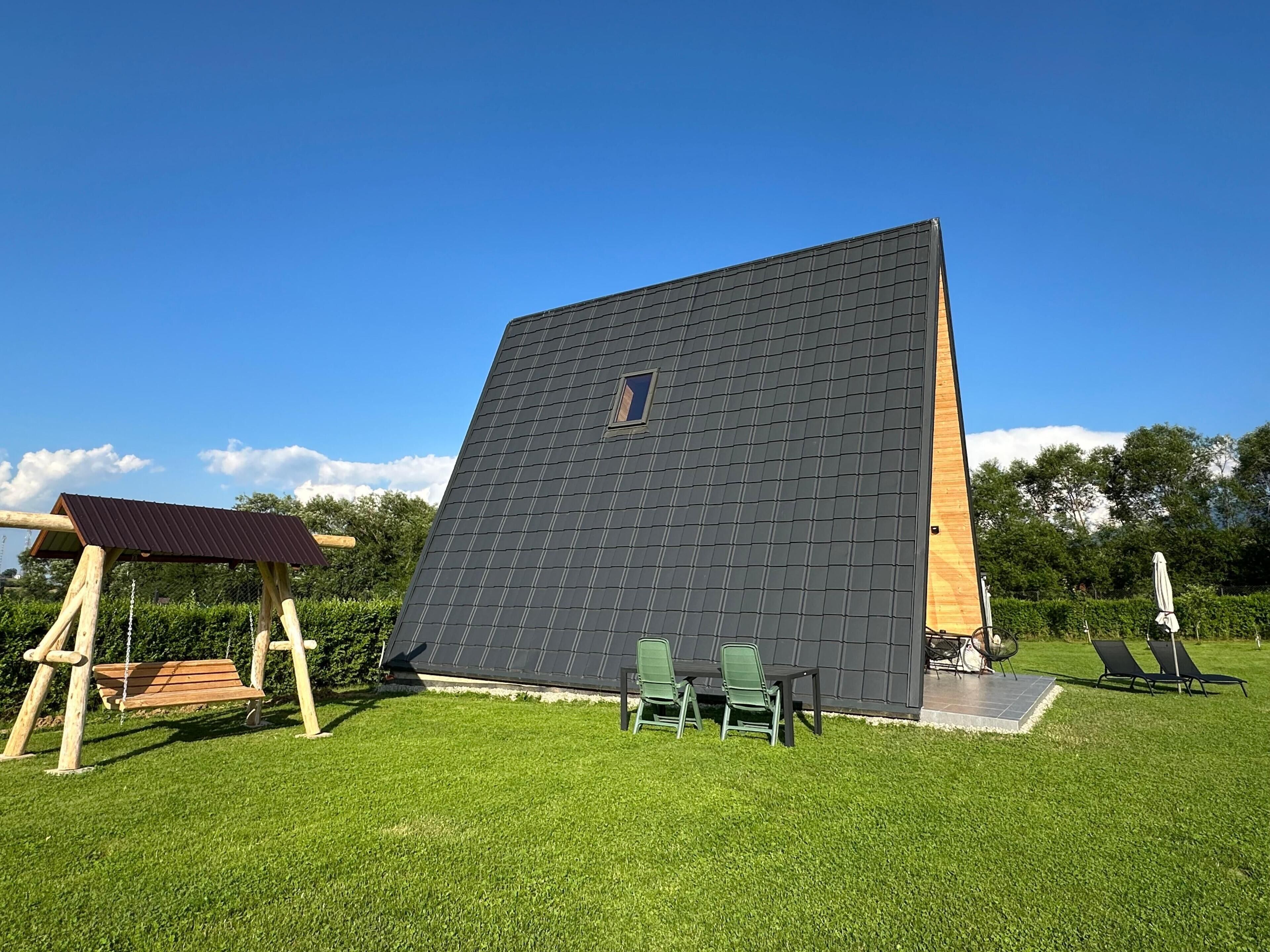 A modern building with a sloped roof, a small window, and a patio area with chairs and a table.